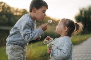 May contain two people blowing dandelion seeds.