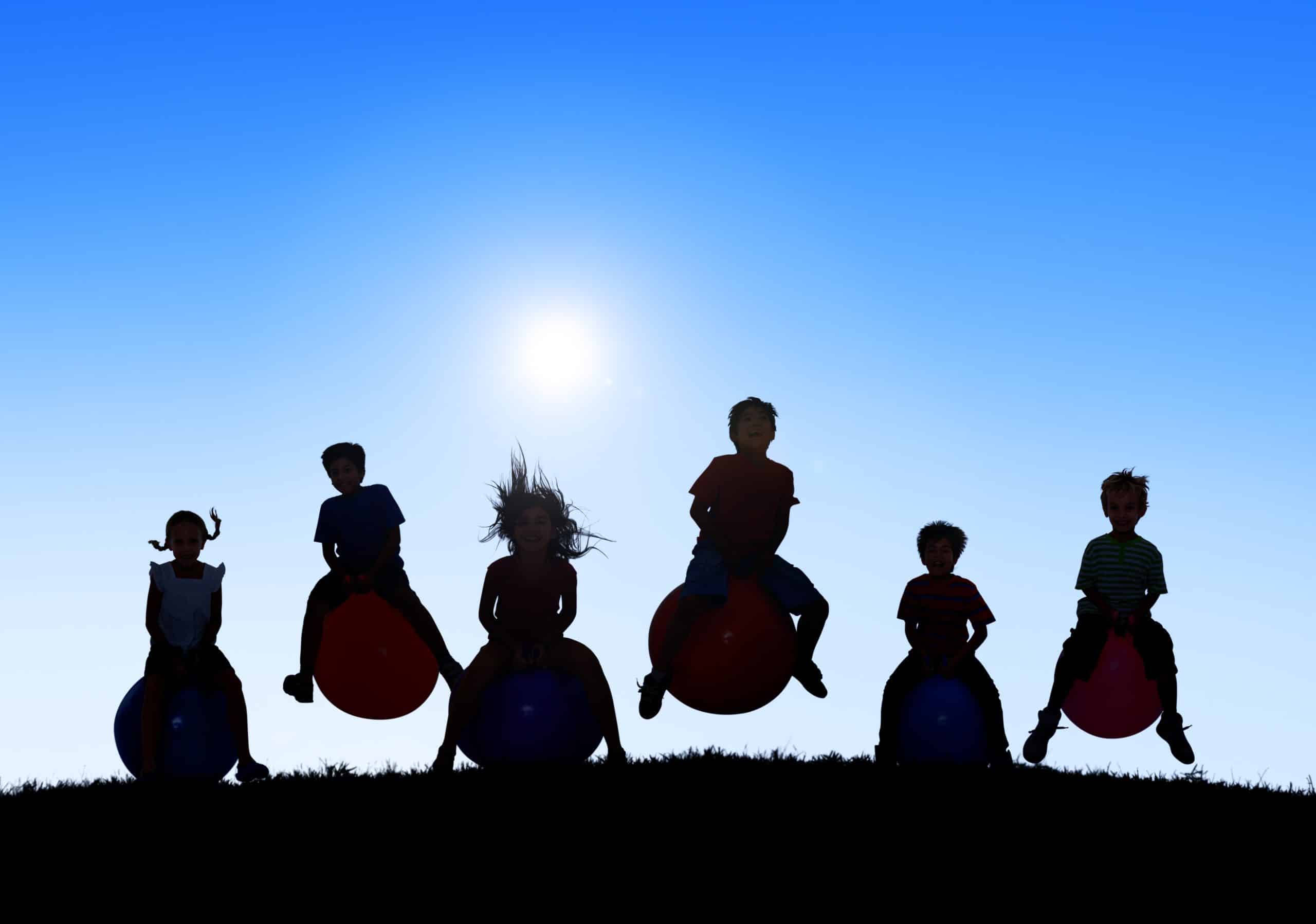 Silhouettes of Children Playing on Balls and Copy Space Above