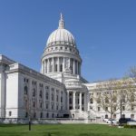 May contain a large capitol building with a dome, lawn, and trees.