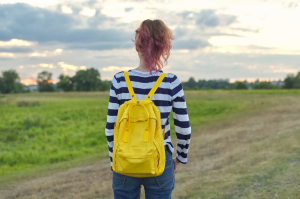 May contain person with yellow backpack and striped shirt outdoors.