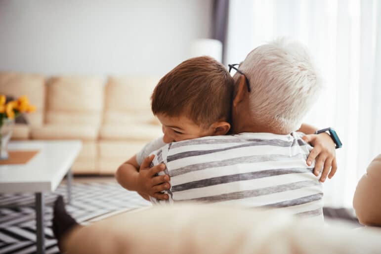 Loving grandfather and grandson enjoying while embracing each other at home.