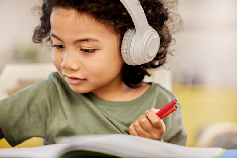 Little boy with headphones focused on drawing a picture